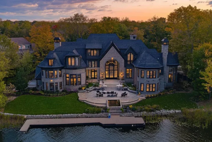 A stunning view of Joe Rogan House located on Lake Austin showcasing its modern farmhouse design and beautiful surroundings.